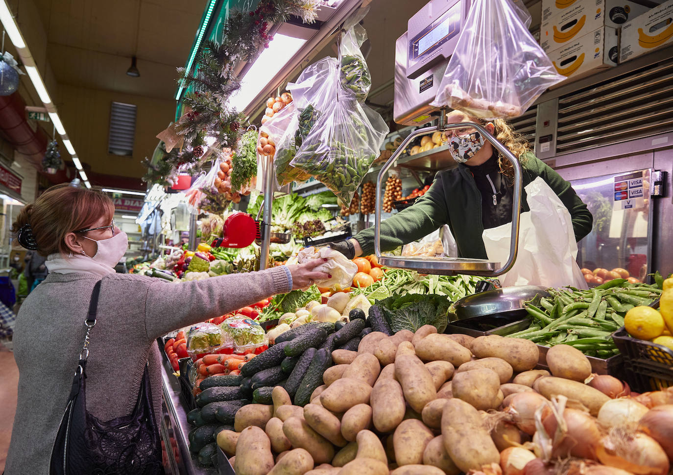 Con la Navidad a la vuelta de la esquina, los valencianos aprovechan para disfrutar del ambiente y realizar las compras en los mercados de la ciudad. La celebración de las fiestas navideñas este año será atípicas y con restricciones por la pandemia del coronavirus. En imagen, el Mercado del Cabaynal este martes.