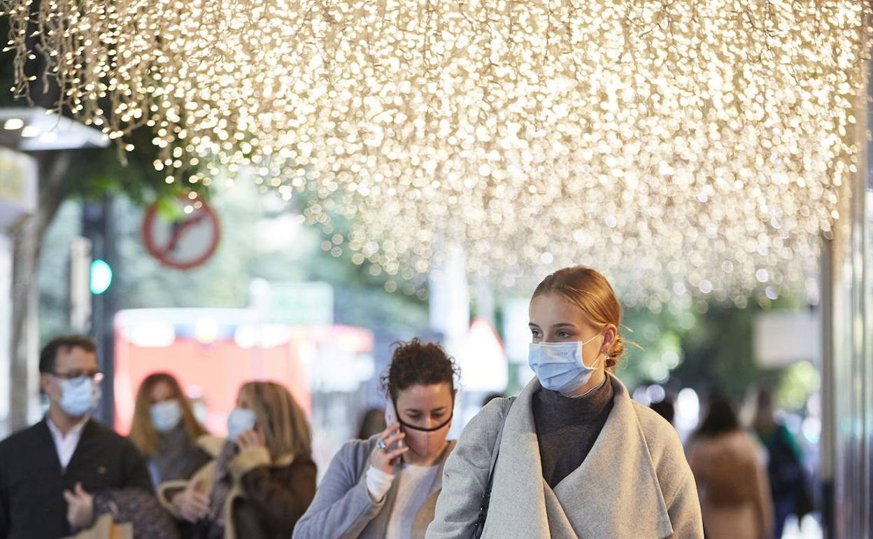 Varias personas pasean por Valencia con las calles iluminadas por la Navidad. 