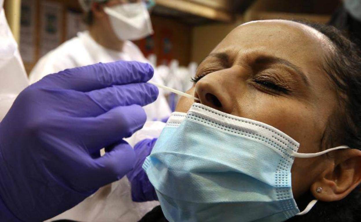 Un sanitario realiza una PCR a una mujer. 