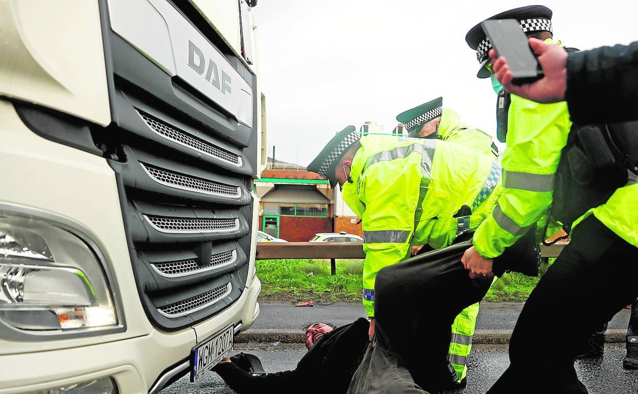 Un policía intenta apartar a un camionero durante una protesta de afectados, ayer, en las inmediaciones del puerto británico de Dover. 