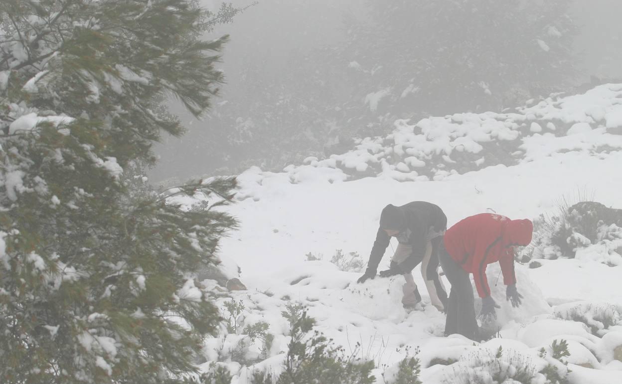 Dos personas juegan con la nieve en la Sierra de la Aitana. 