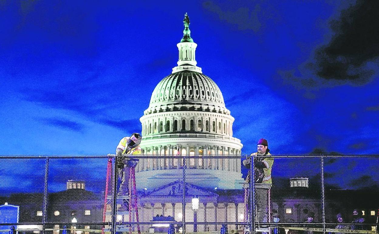 Operarios instalan una valla de seguridad de alta resistencia en torno al Capitolio durante los preparativos para el acto de investidura de Biden.