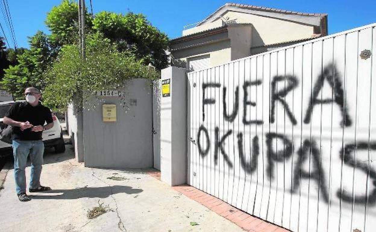 Un vecino ante la puerta de una vivienda donde se reclama a los okupas que se marchen. 