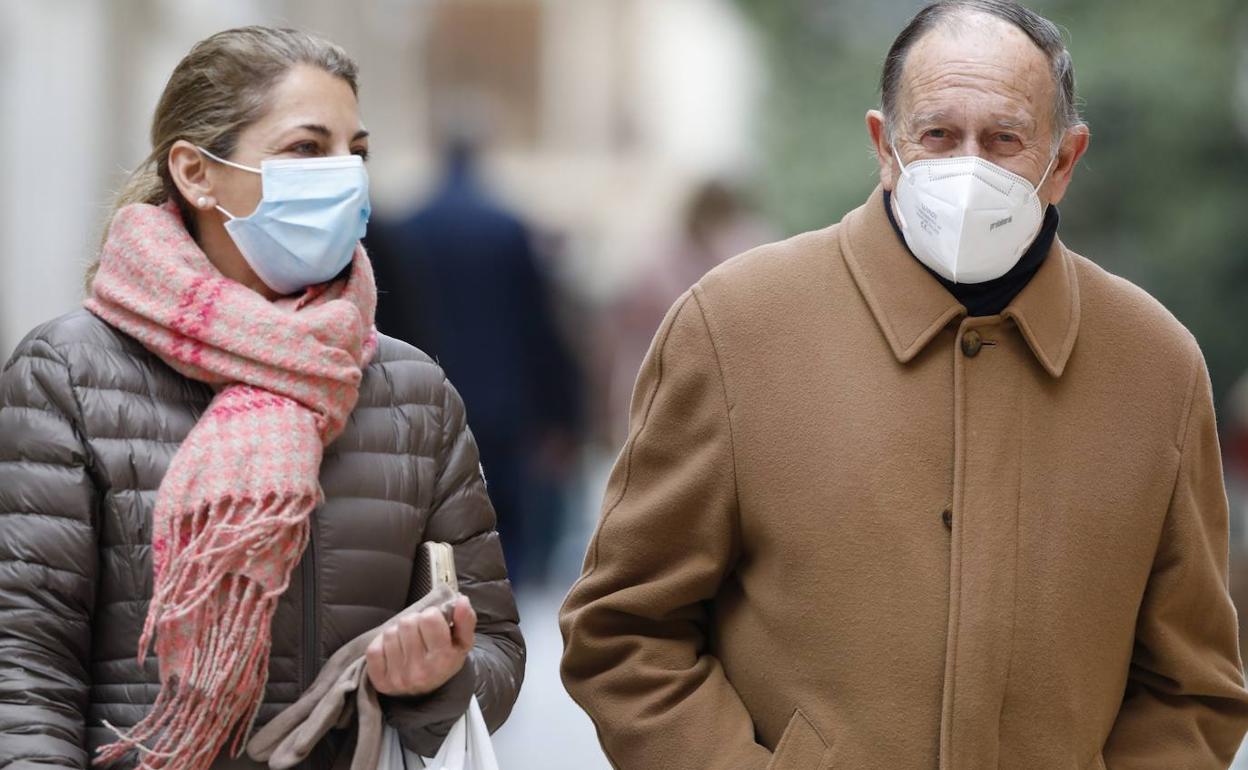 Dos personas pasean por Valencia con mascarilla.