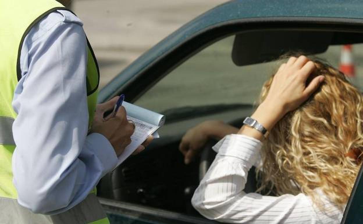 Un agente de Tráfico multa a una conductora.