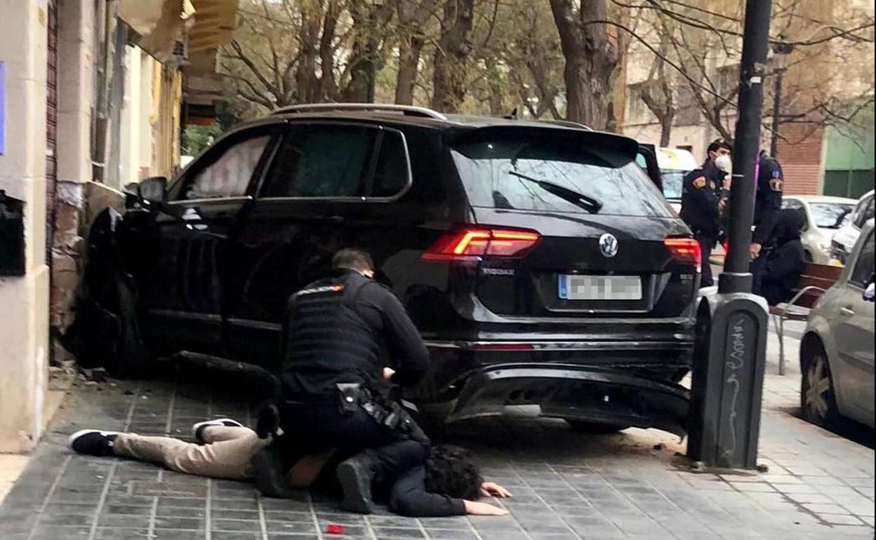 Momento en que el joven a la fuga es reducido por la policía junto a su coche empotrado, en la calle Jaca de Valencia. 