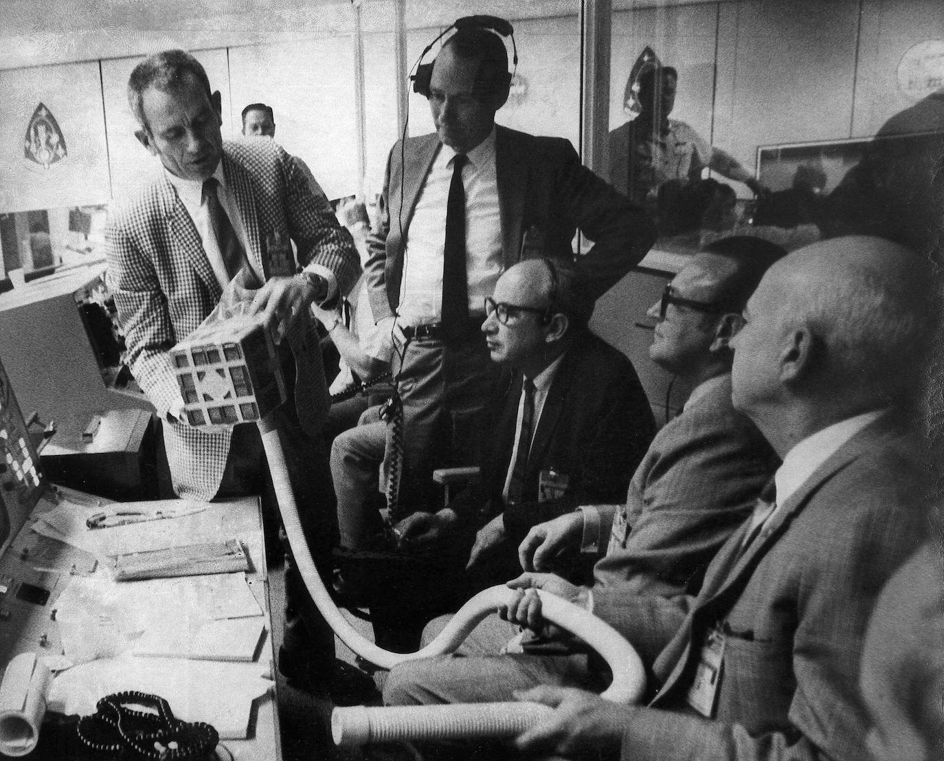 Donald Slayton (i) muestra a otros dirigentes de la NASA la canasta de hidróxico de litio, provista de una manguera, que se utilizará para que puedan respirar los tripulantes del Apolo 13.
