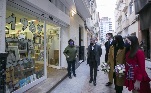 Las falleras mayores Sandra Faus y Alba Ramón y representantes de las Fallas de Gandia contemplan un escaparate. 