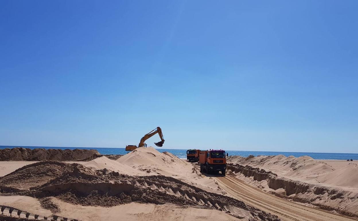 Una pala excavadora y dos camiones extraen arena en la playa de Xeraco en mayo de 2018. 