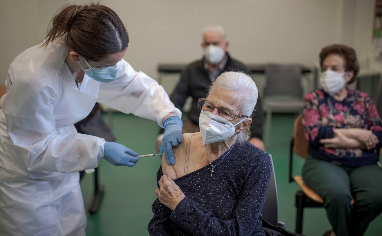 Una enfermera vacuna a una anciana. 