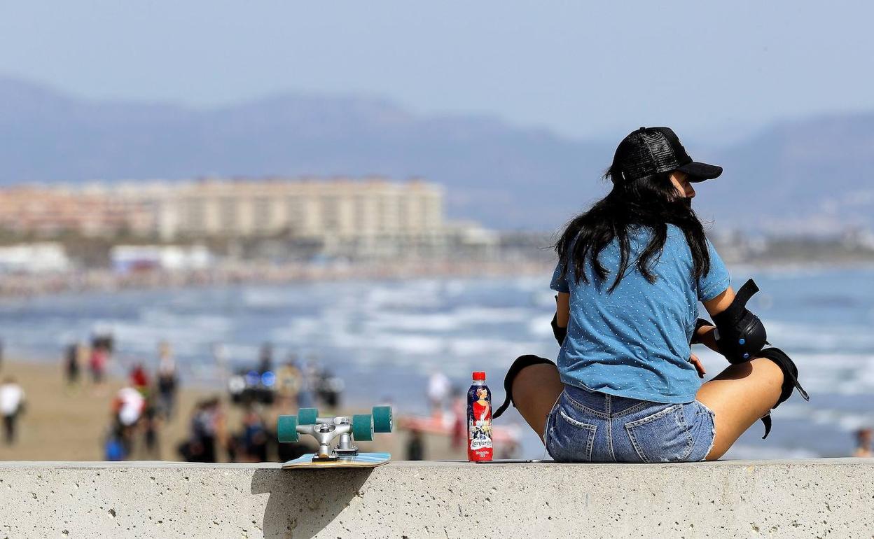 Una joven observa la playa de Las Arenas desde el espigón de la Marina del Puerto de Valencia. 