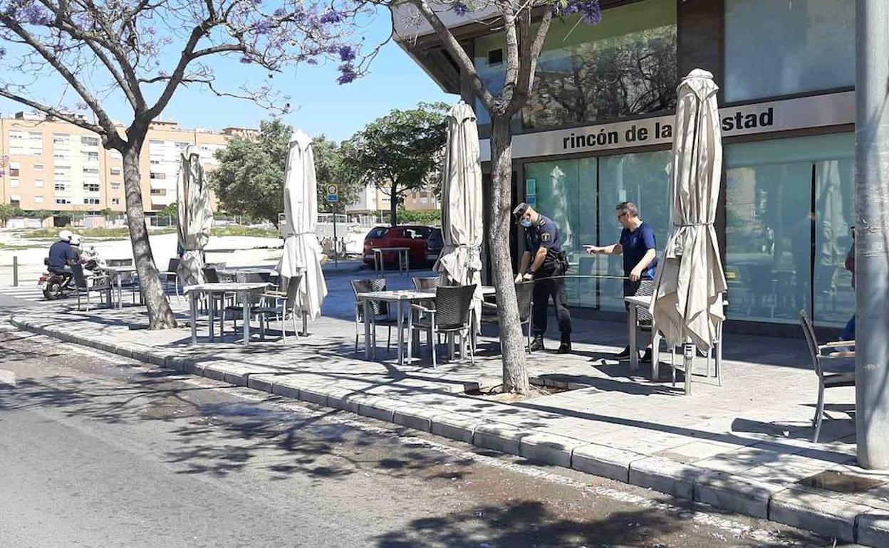 Un policía mide la distancia entre mesas en una terraza de Alicante. 