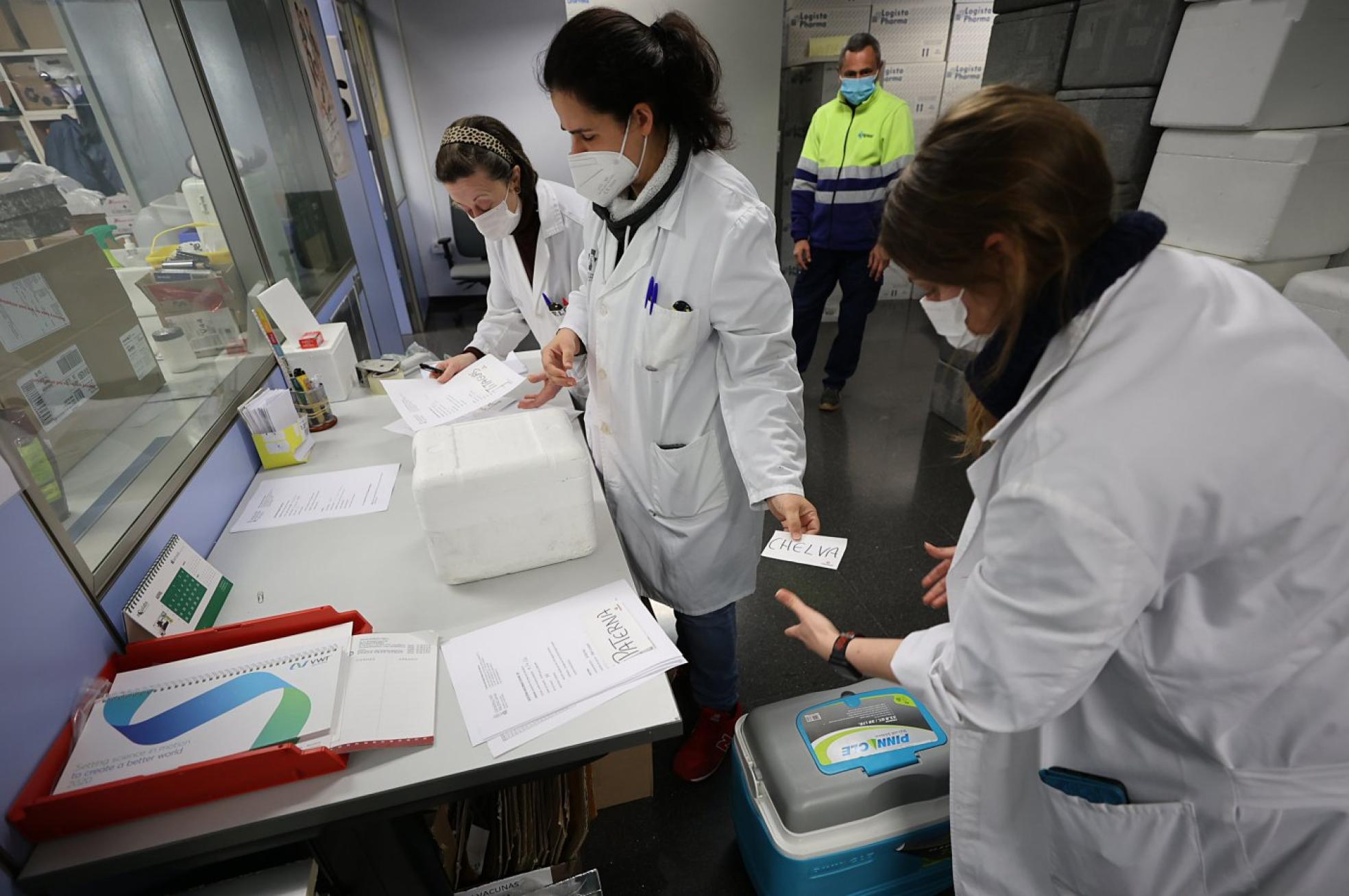 Proceso. Vistas del almacén donde se guardan los viales con los trabajadores distribuyendo las dosis y de un punto de vacunación en Valencia. 