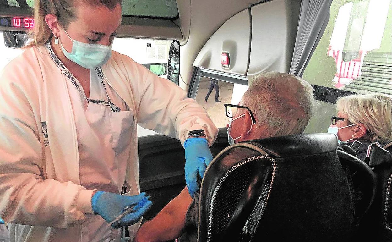 Personal sanitario del 'vacunódromo' de la Ciudad de las Artes y las Ciencias administra una dosis en el interior de un autobús por la lluvia.