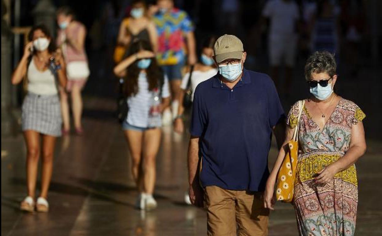 Varias personas con mascarilla caminan por Valencia.