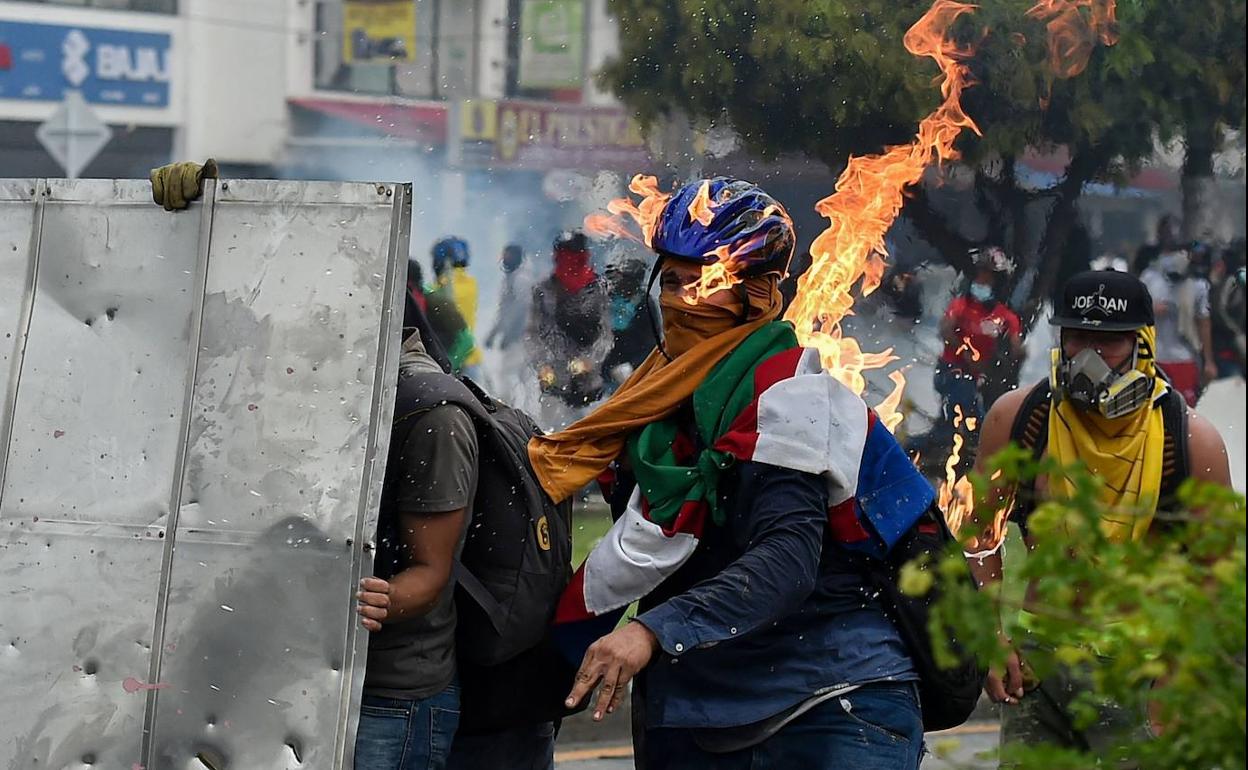 Un manifestante es golpeado por un cóctel molotov durante los enfrentamientos con agentes de la Policía en Cali.