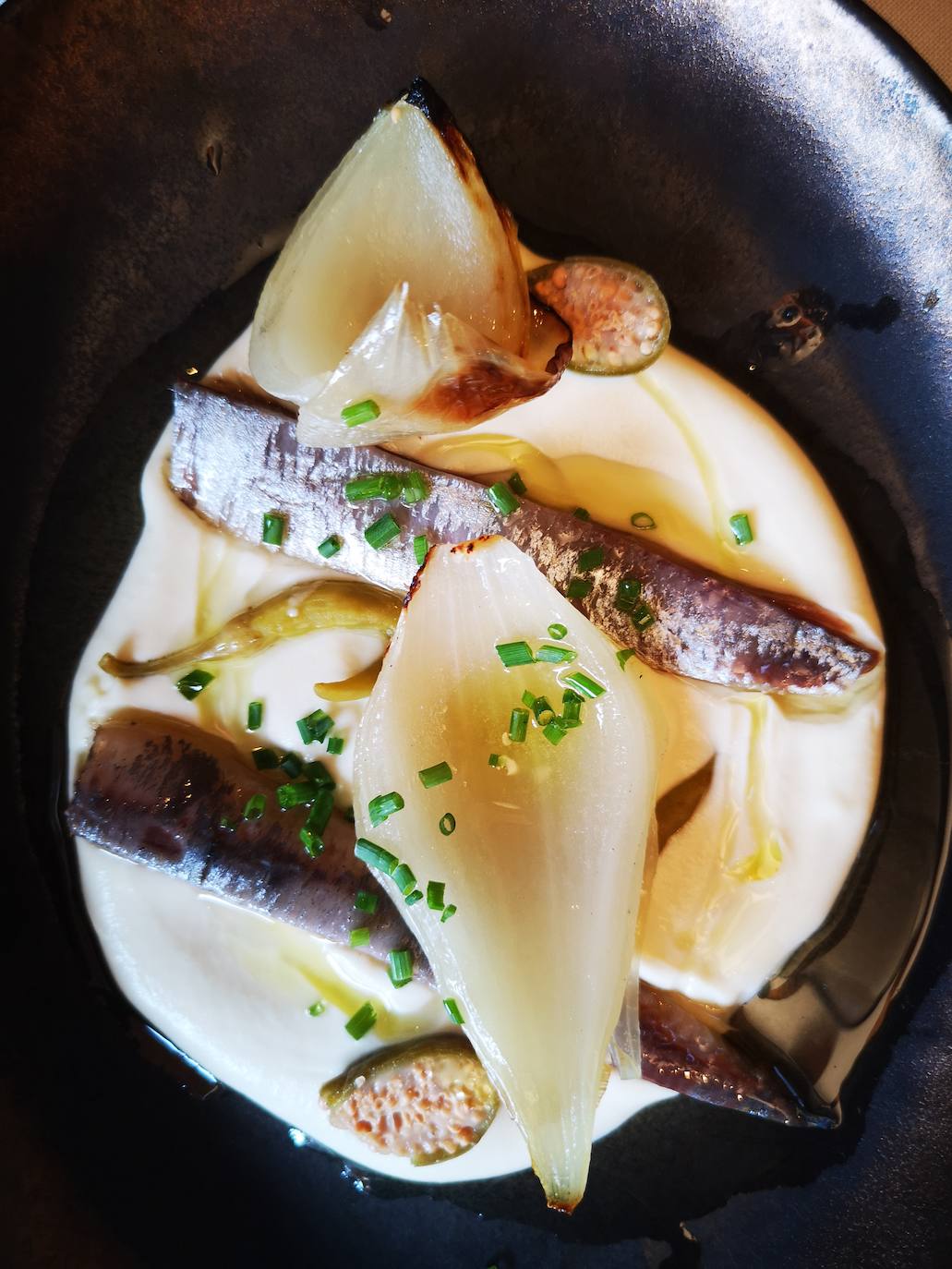 Primer entrante, unos lomos de sardina ahumada con cebolla tierna a la brasa, piparras y crema de suave de almendras