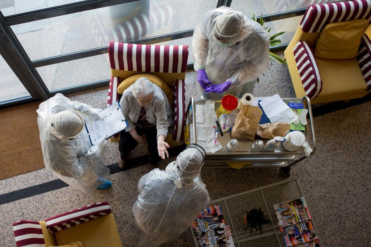 Sanitarios con trajes de protección EPI atienden a una interna de una residencia de Barcelona. EFE/ Quique García