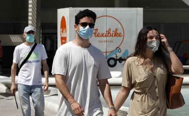 Una pareja con mascarilla pasea por Valencia. 