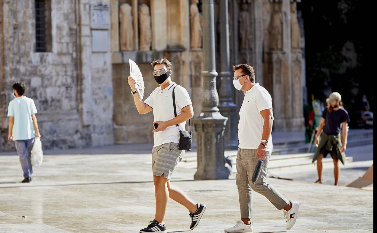 Dos hombres pasean por la plaza de la Virgen