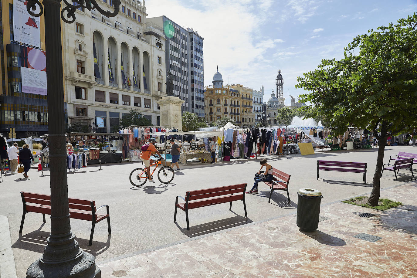 Protestas, mercadillos y restos de instalaciones se mezclan junto a la plaza del Ayuntamiento. Comerciantes y vecinos de la zona insisten en los problemas para acceder en coche mientras el monolito del 15M sigue protegido por vallas.