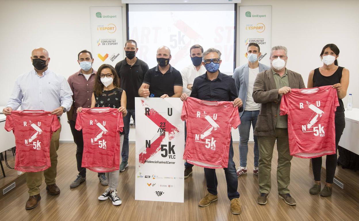 Miembros de la organización de la 5K muestran la camiseta de la carrera. 