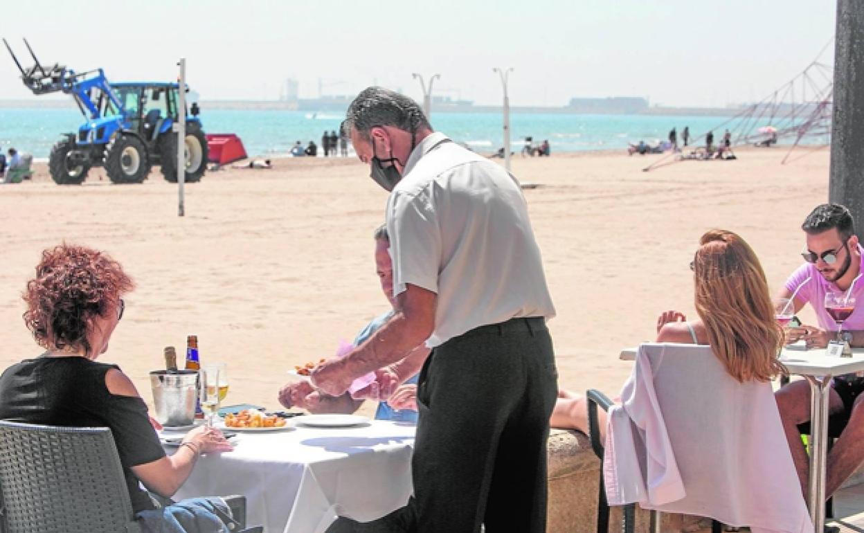 Varios clientes disfrutan de los espacios al aire libre, ayer por la mañana, en los restaurantes del Paseo Marítimo de Valencia. 