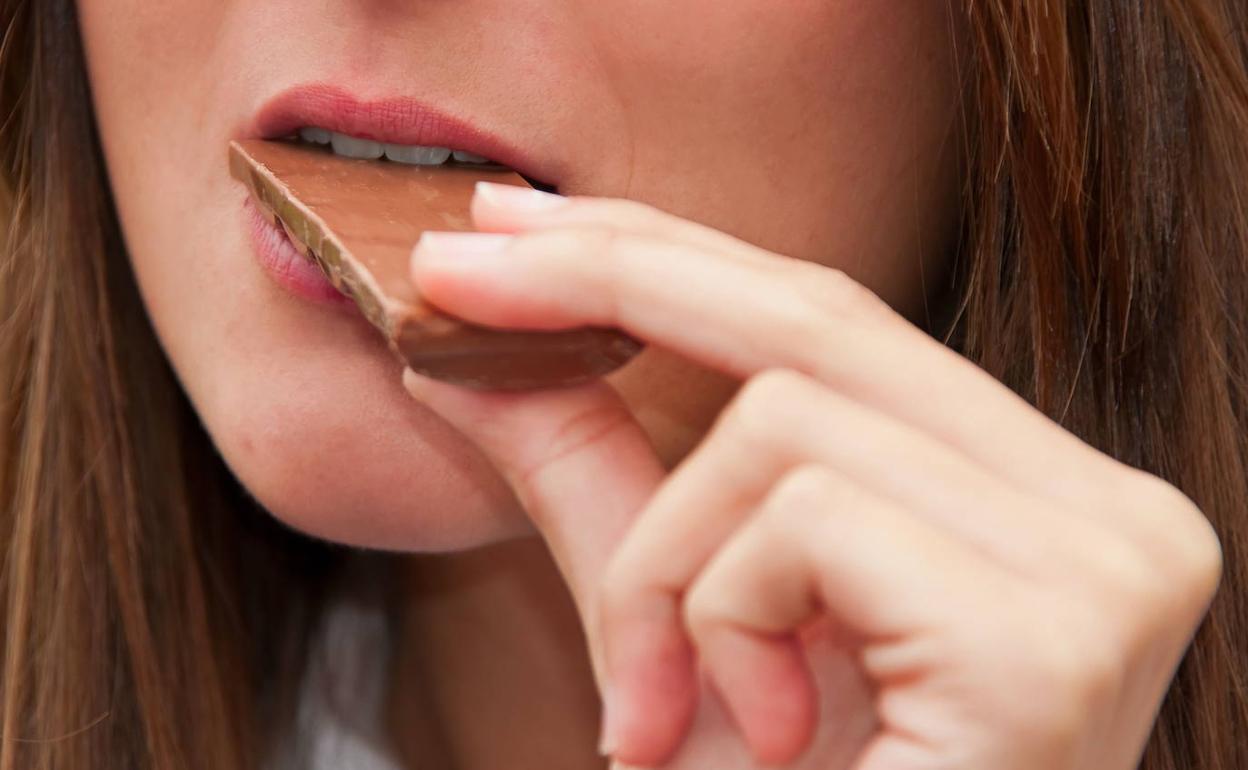 Una mujer comiendo chocolate. 