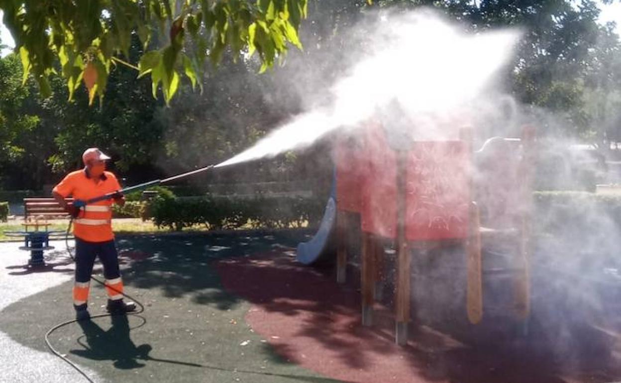 Un operario limpia un parque infantil. 