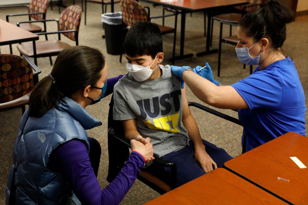 Una mujer sostiene la mano de su hijo mientras recibe la vacuna de Pfizer en un centro escolar de Michigan, en Estados Unidos. 