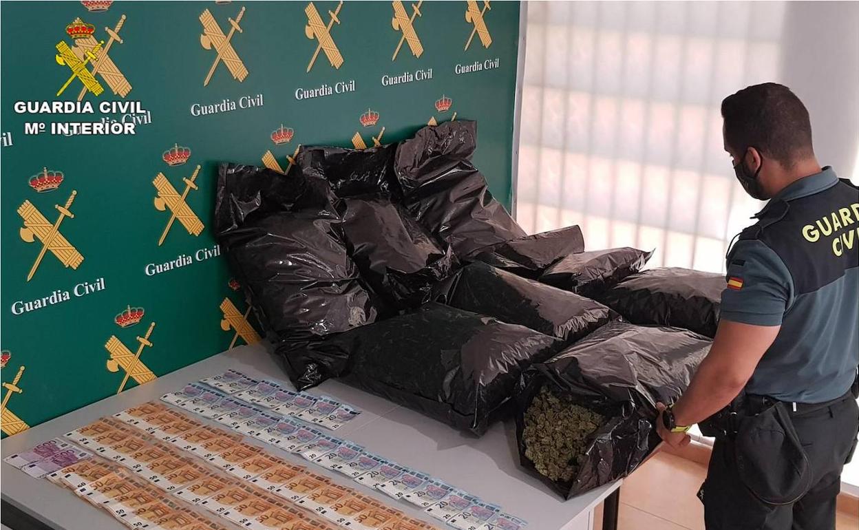 Un agente con la droga y el dinero intervenido. 