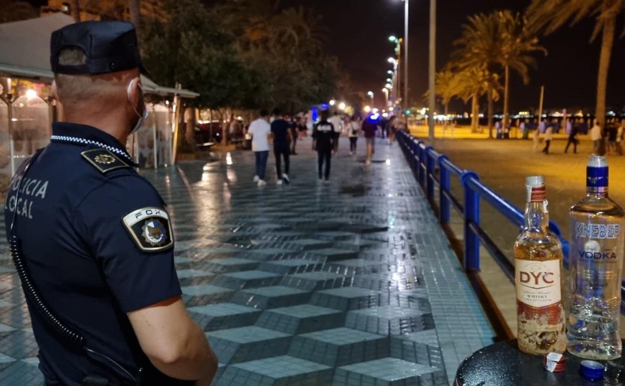 Un agente, tras disolver un botellón en la playa del Postiguet de Alicante. 