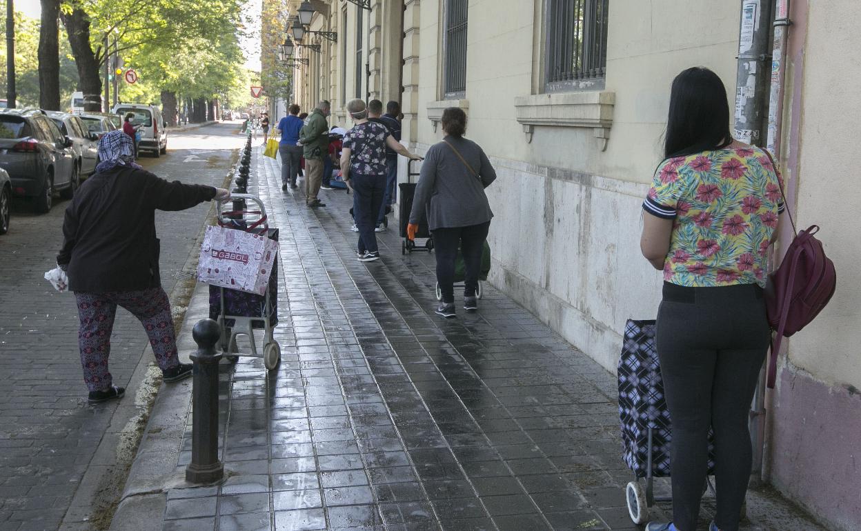 Un grupo de personas hacen cola junto a la sede de Casa Caridad en Valencia, en el Paseo de la Petxina. 