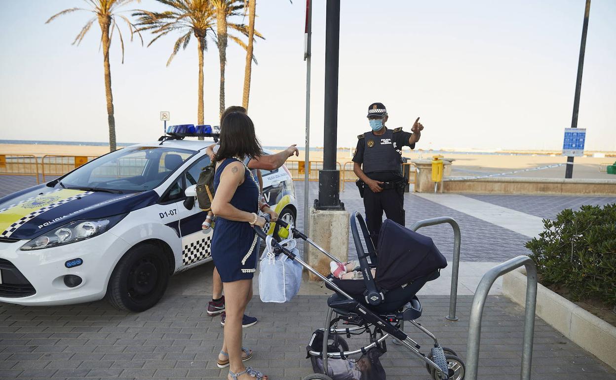 Un agente de la Policía Local advierte a una pareja sobre el cierre de las playas en la noche de San Juan del año pasado 