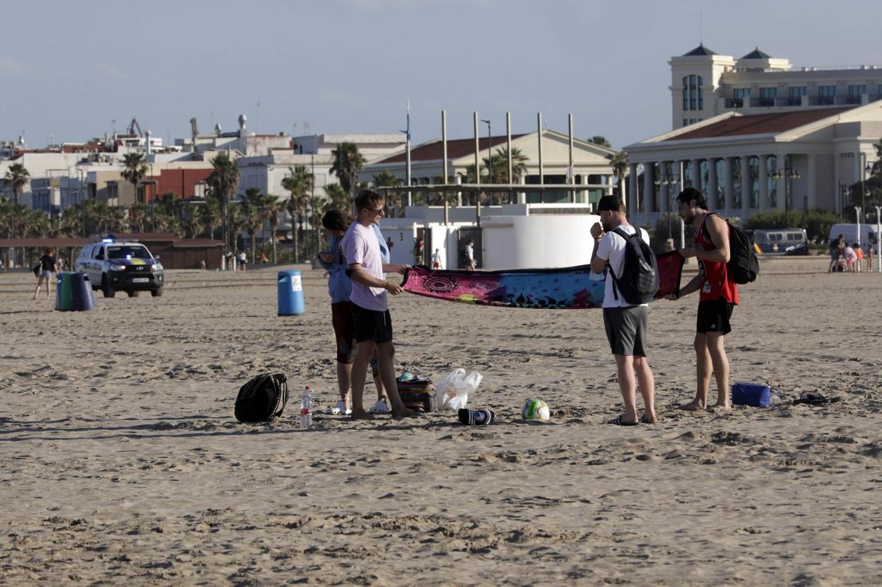 Varios jóvenes recogen tras el aviso de la Policía Local para desalojar la playa de la Malvarrosa de Valencia ante la prohibición de la celebración de San Juan. Irene Marsilla