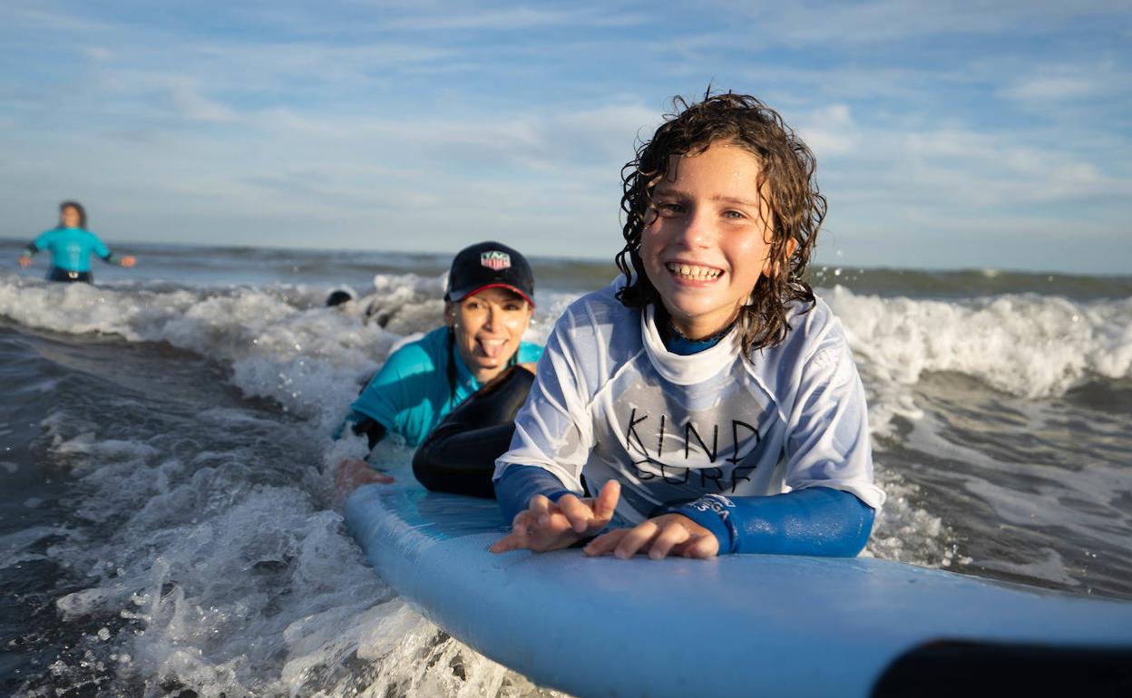 Un niño practica surf en la playa. 