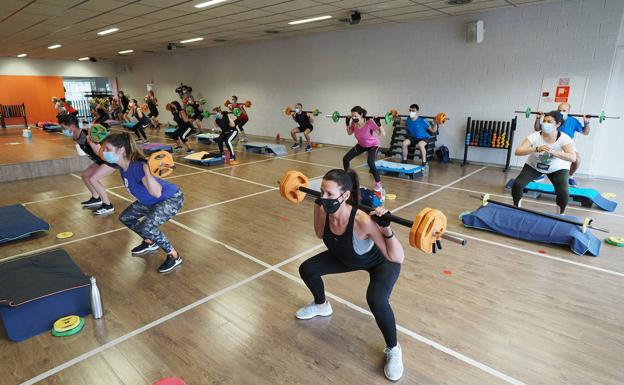 Un grupo de personas realiza deporte en la sala de un gimnasio.