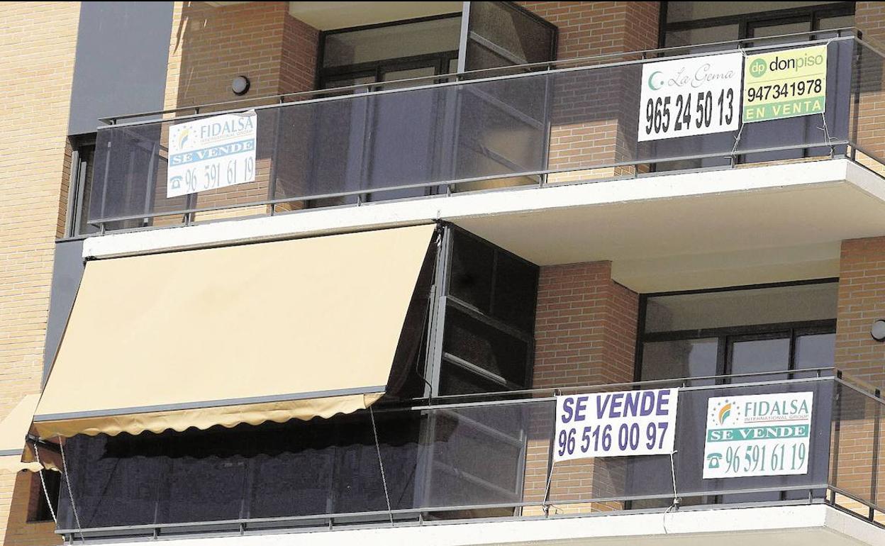 Varios carteles para vender o alquilar pisos en Alicante.