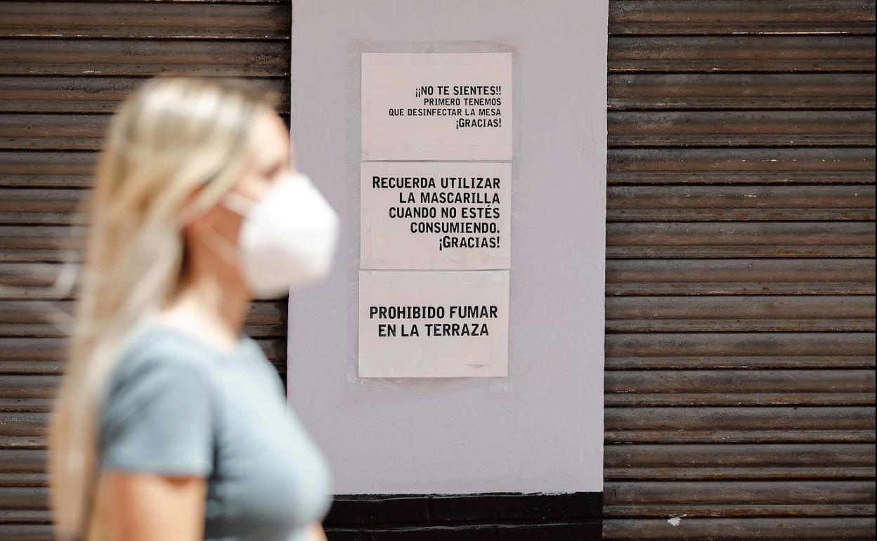 Una joven pasa por delante de la persiana bajada de un restaurante.