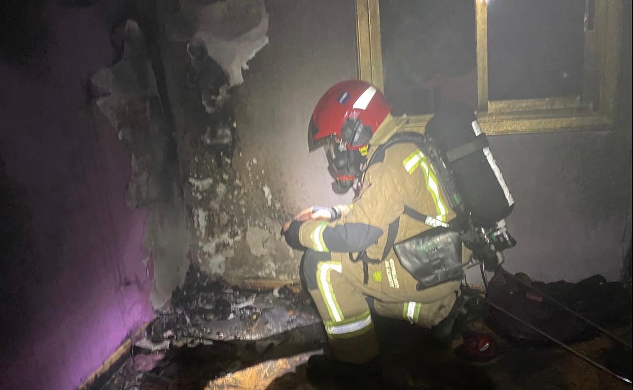 Los bomberos intervienen en la habitación más afectada tras las llamas. 