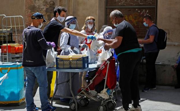 Misioneros de la Caridad y voluntarios reparten comida en el comedor Reina de la Paz del barrio del Raval de Barcelona. 