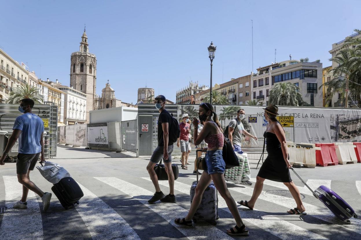 Un grupo de turistas pasa cargado con maletas por la plaza de la Reina de Valencia. irene marsilla