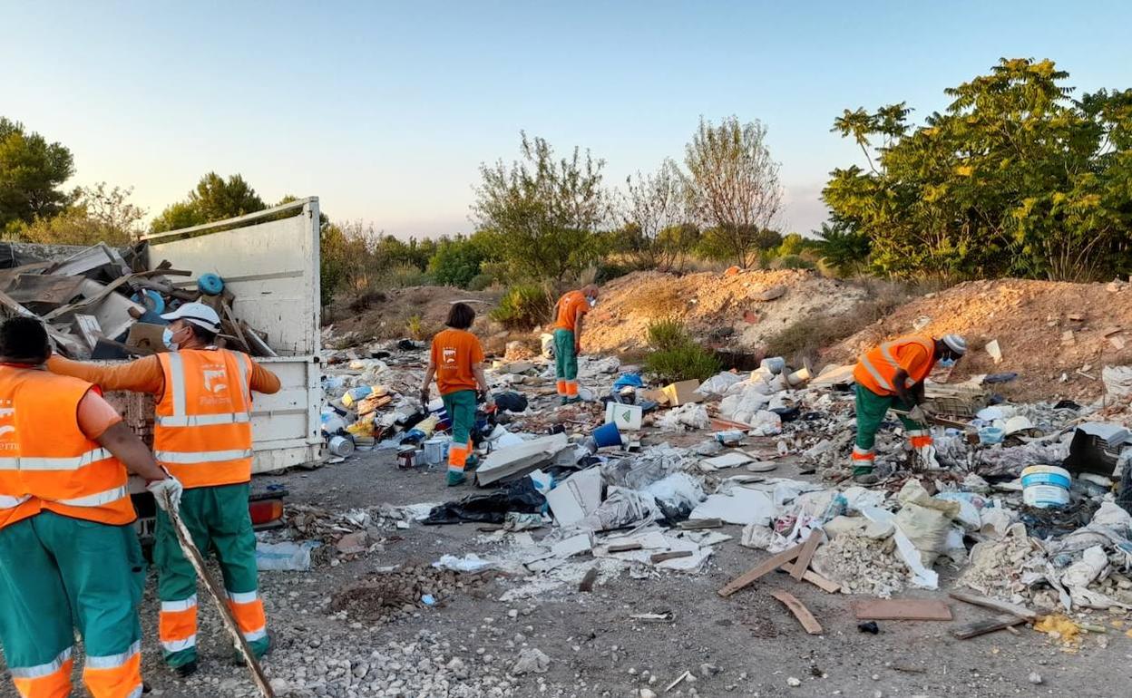 Los operarios trabajan en la limpieza del vertedero. 