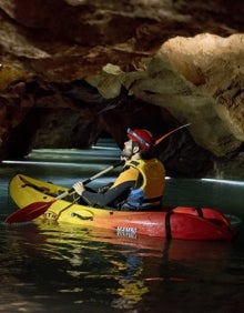 Imagen secundaria 2 - Arriba, una kayakista recorre las galerías de las cuevas. Abajo a la izquierda, un barquero guía a un grupo por las grutas. Abajo a la derecha, un kayakista observa el techo de las cuevas. 