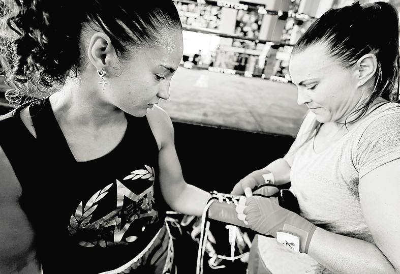 Ayuda. Khatarina, que fue campeona mundial, le coloca los guantes.