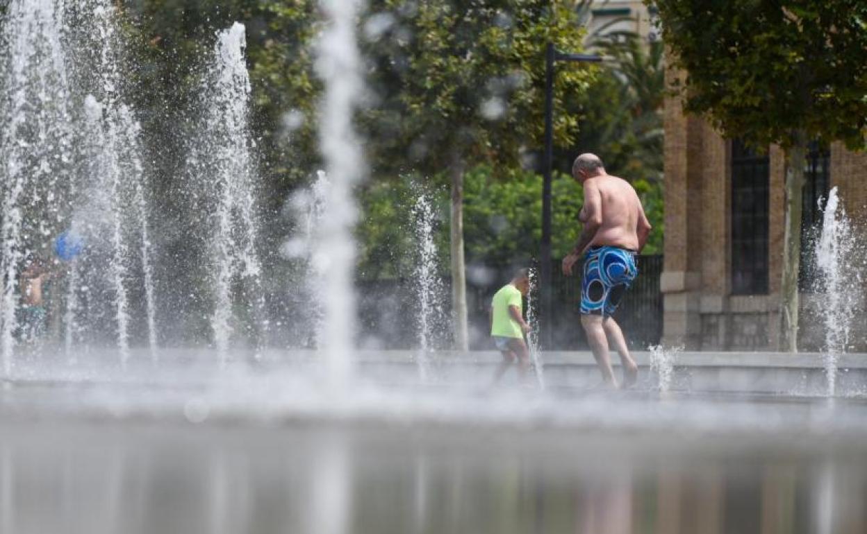 Dos personas se refrescan en una fuente del Parc Central