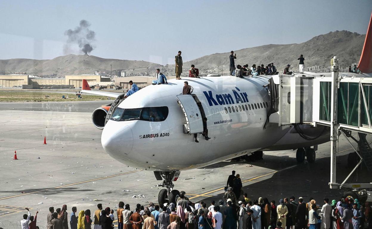 Decenas de personas rodean un avión que trata de despegar del aeropuerto de Kabul. 