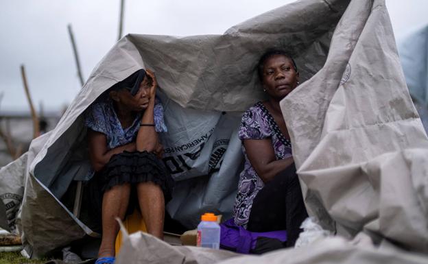 Dos mujeres se protegen con una lona de plástico de las lluvias que ha dejado en el sur de Haití la tormenta 'Grace'. 