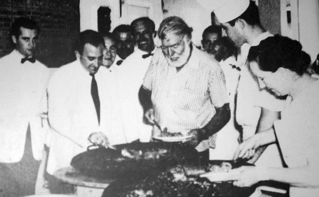 Ernest Hemingway sirviendo un plato de paella en el establecimiento. 