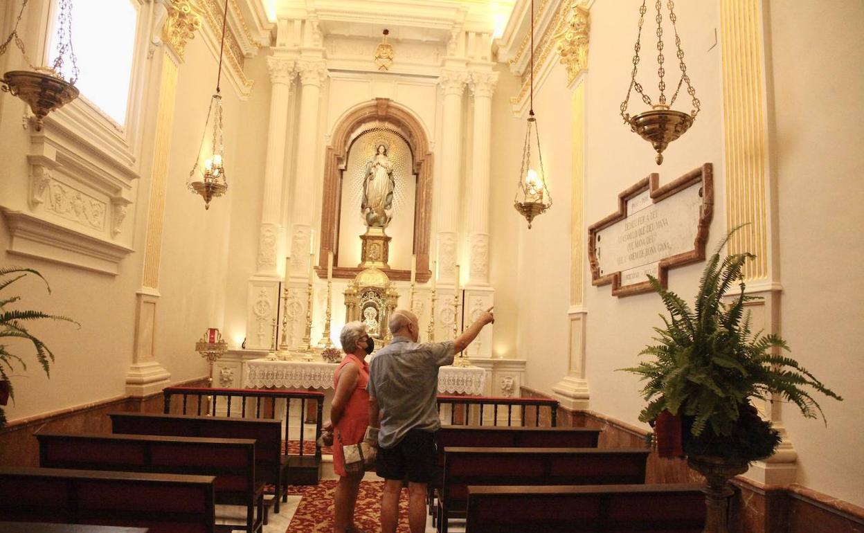 Un par de personas contemplan en la restaurada capilla del Santísimo Sacramento la inscripción sobre el Pare Pere. 